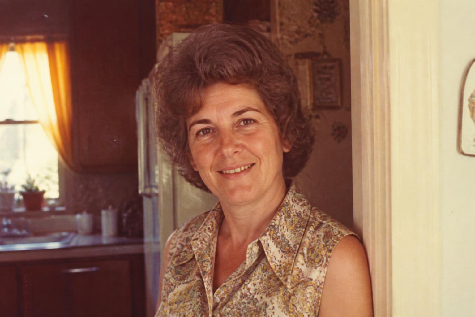 A faded 1970s portrait of Eleanor smiling in her kitchen doorway